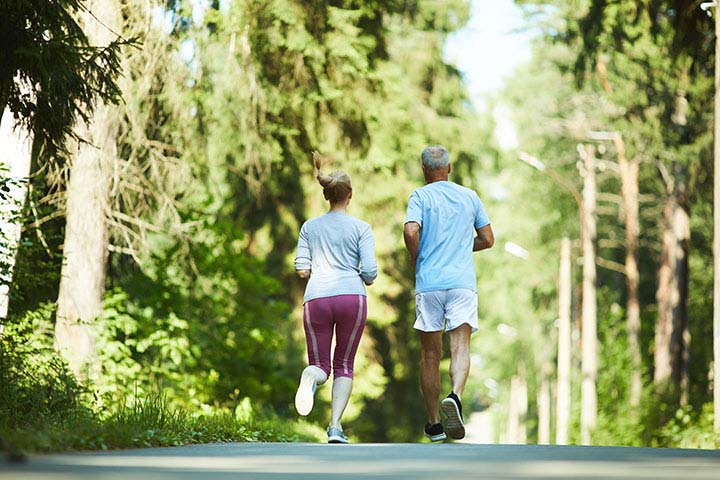 Exercise Essentials: Active Steps for Heart Health; Back view of aged spouses in activewear running down road in park between trees on sunny day