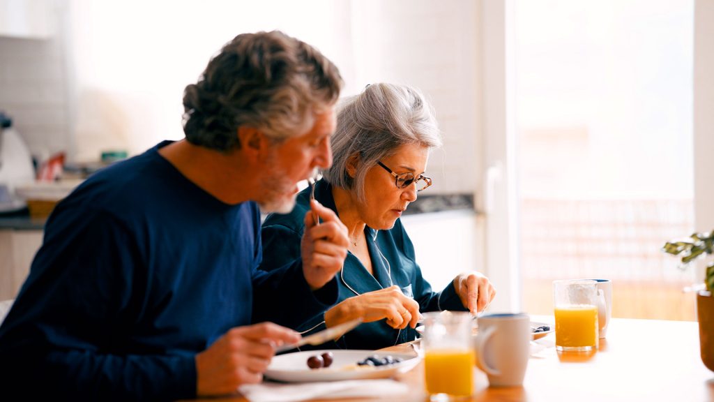 Older couple eating a healthy breakfast together at home in the kitchen
