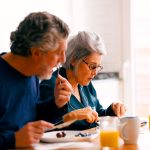 Older couple eating a healthy breakfast together at home in the kitchen