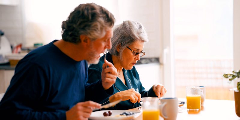 Older couple eating a healthy breakfast together at home in the kitchen